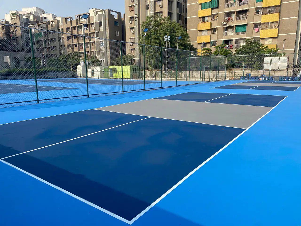 Site içinde şehir manzarasına bakan mavi tonlu akrilik kaplamalı spor sahaları