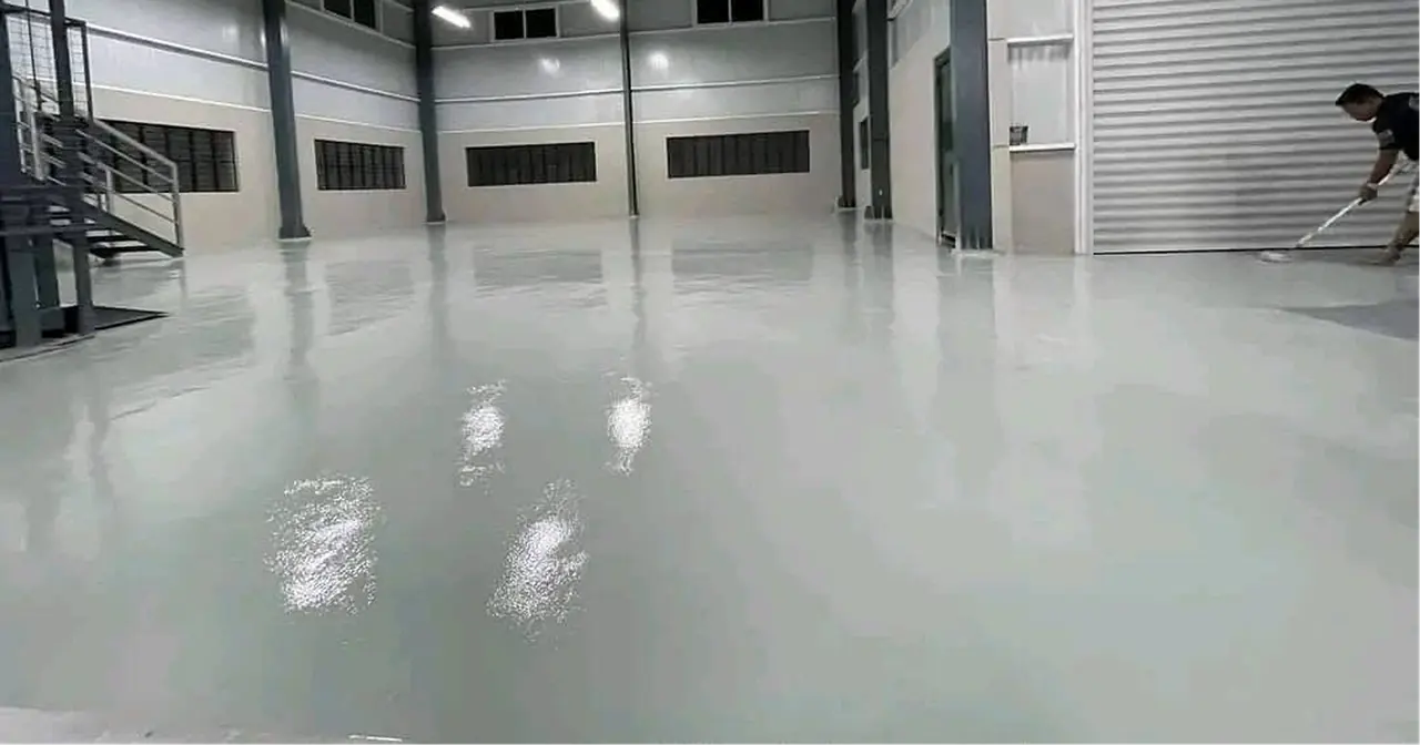 Uygulamacının endüstriyel hol zemininde epoksiyi ruloyla yayması